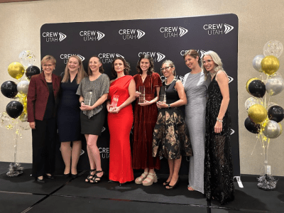 Eight ladies standing in front of CREW Utah banner at Gala event
