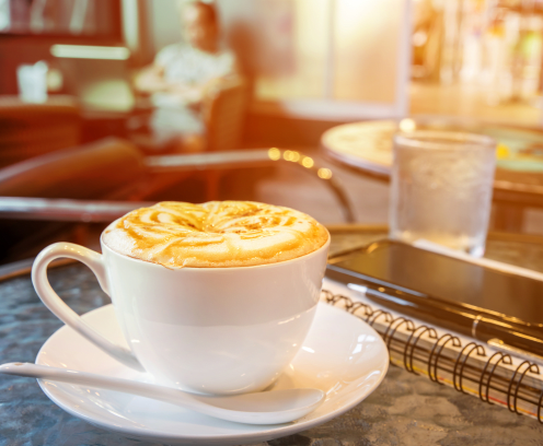 coffee cup on table with notebook, pen, smartphone, cafe