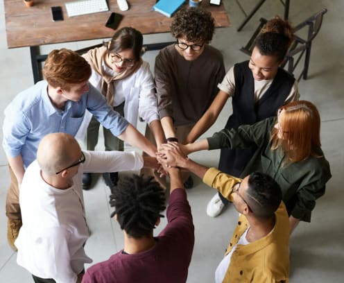People standing in a circle with hands in the middle