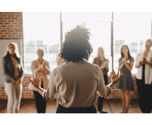 Businesswoman with arms outstretched talking to a small group