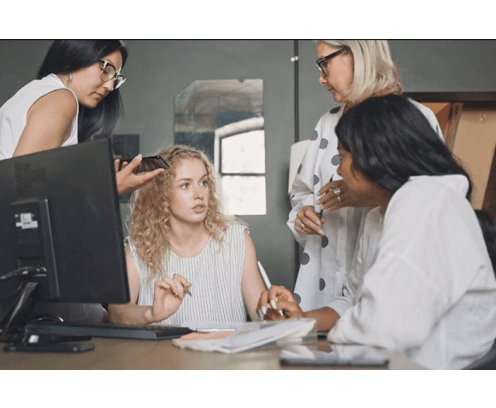 four women discussing around computer
