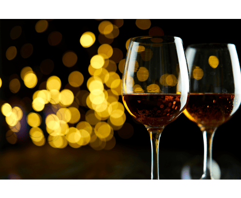 Two glasses of sparkling wine or champagne to celebrate New Year, Merry Christmas or Anniversary with a bokeh effect background. The yellow of the wine and lights stand out against a dark background.