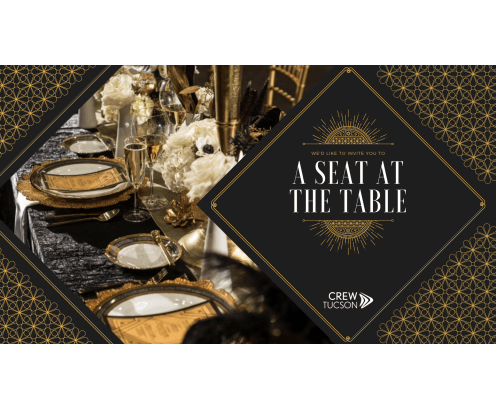 an elegant table set with golden plates and golden silverware and flowers and wine glasses