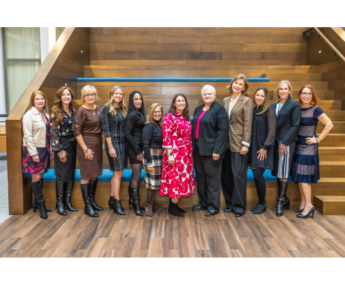 Twelve professional women standing together, posing and smiling.