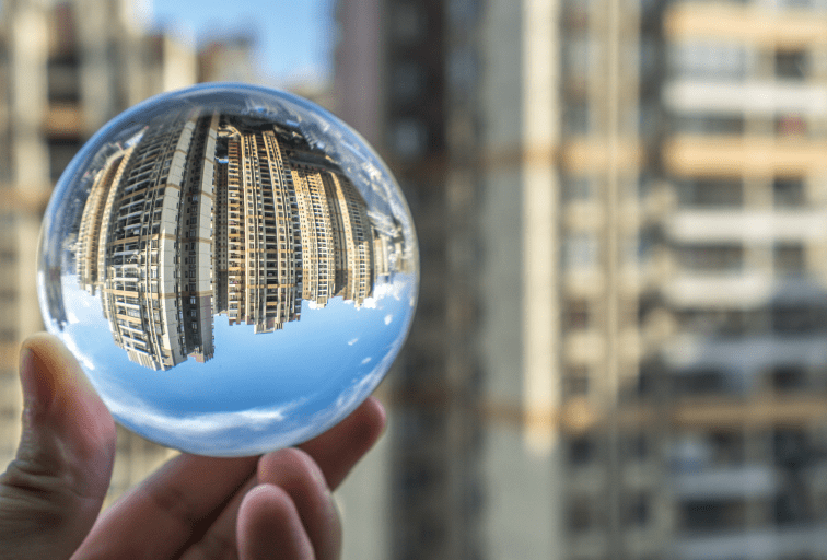 hand holding a glass ball reflecting city buildings in the background