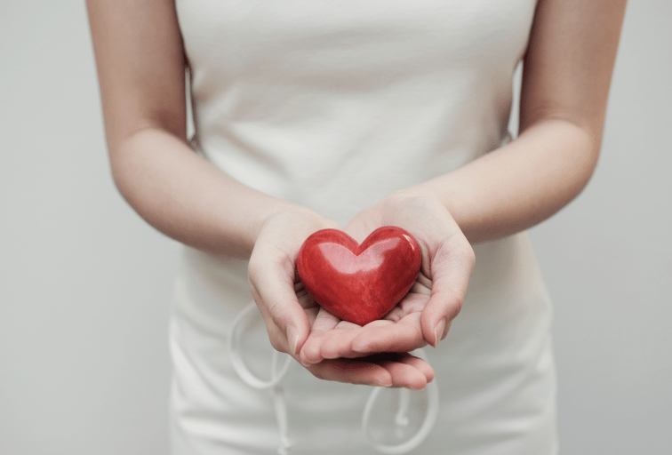 woman offering a red heart-shaped stone to camera