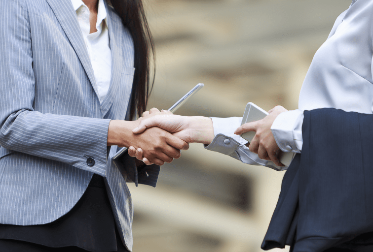 business women shaking hands with iphone and tablets in their hands