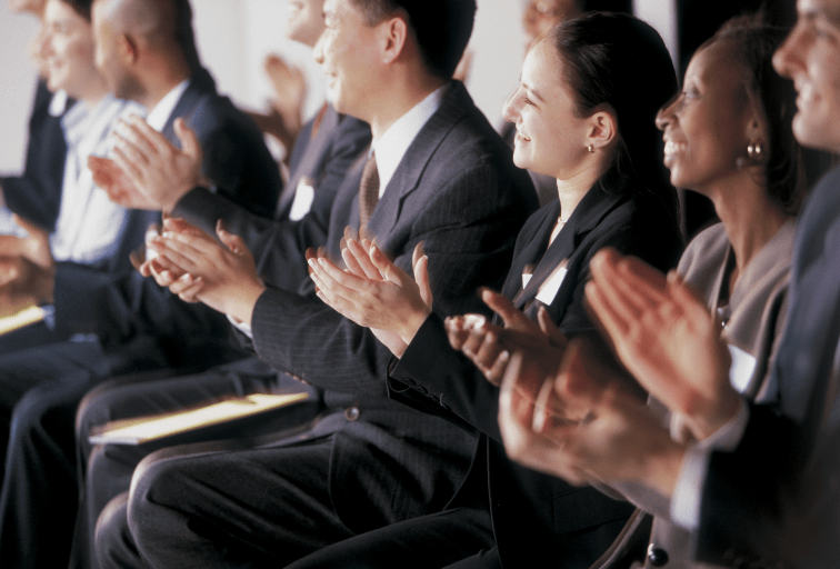 group of businesspeople in suits clapping in audience