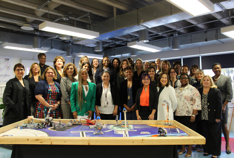 Group photo of college students and professionals over a worktable at a UCREW event