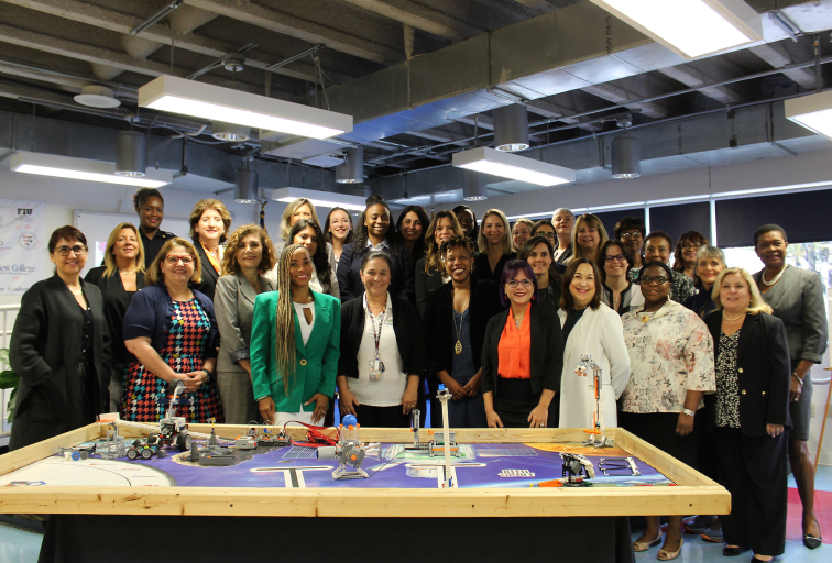 Large group of businesswomen posing behind large project table