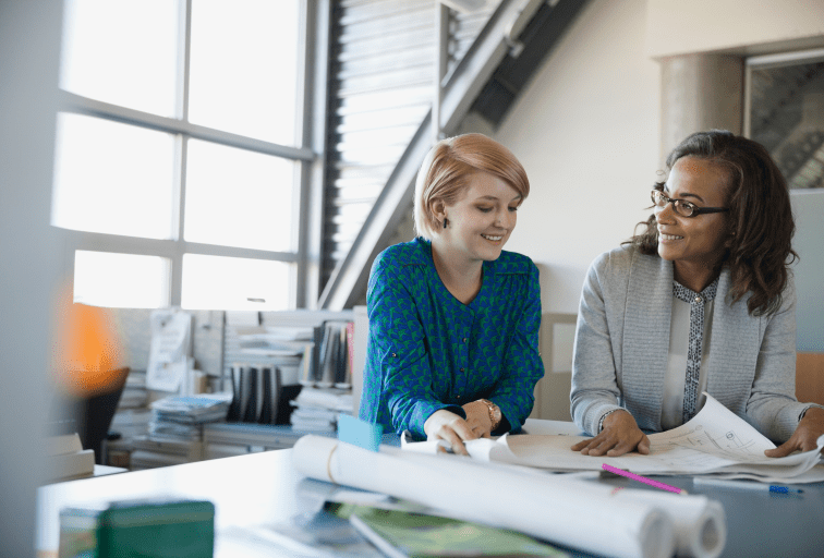 diverse women mentoring over blueprints