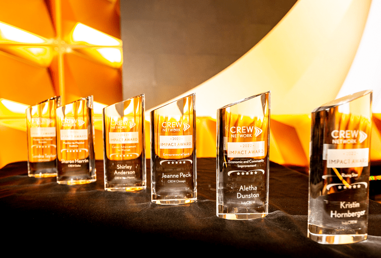 six glass CREW Impact Awards lined up on a table