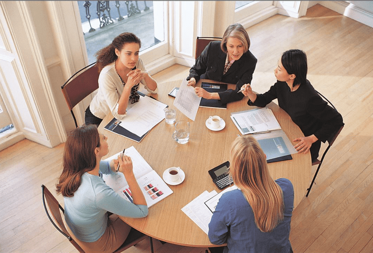 overhead view of businesswomen at a round table discussing documents