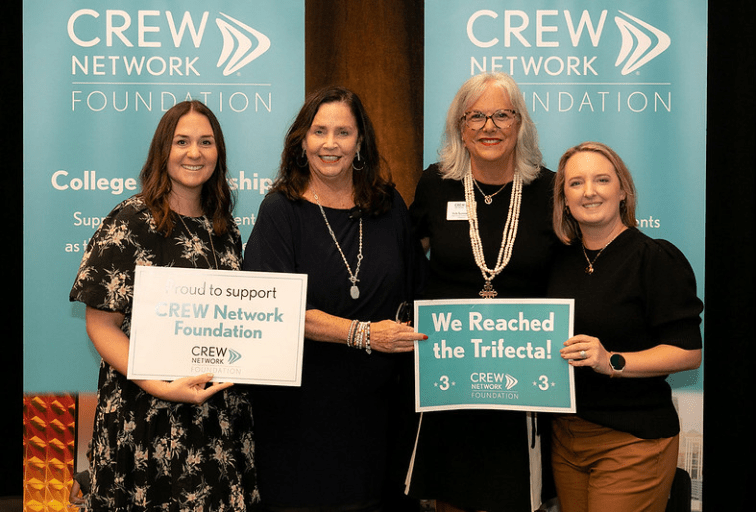 Women holding a We Reached the Trifecta sign