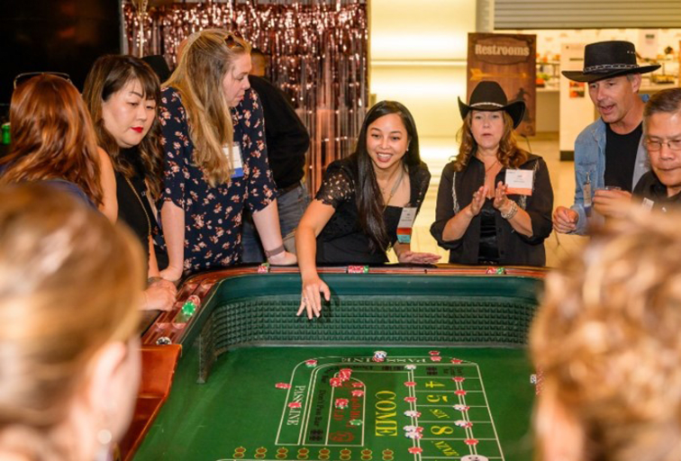 Gamblers surrounding a craps table, cheering and clapping for the person rolling the dice