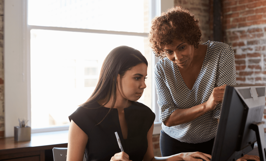 Two Businesswomen Working On Computer In Office mentor concept