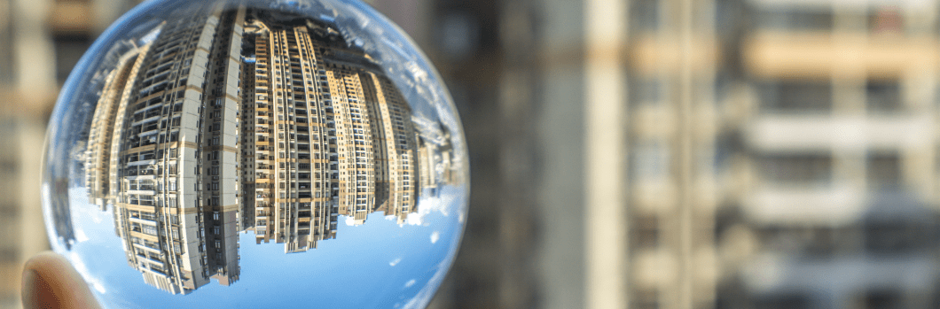hand holding a glass ball reflecting city buildings in the background