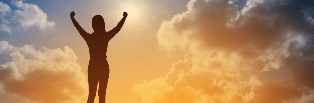 silhouette atop mountain with dimming sunlight and clouds