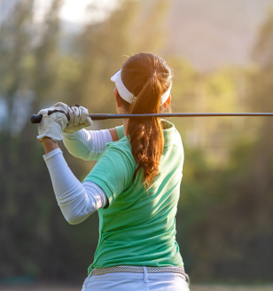 Sport Healthy. sporty woman golf player doing golf swing tee off on the green sunset evening time, she presumably does exercise. Healthy and Lifestyle Concept.