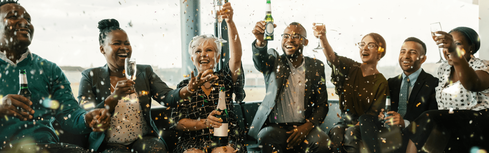 A festive multi ethnic group of people smiling, toasting with sparkling wine and beer. Celebrating the end of the working year and to the new year ahead