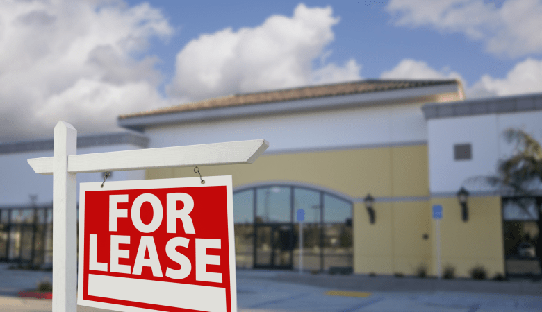 Vacant Retail Building with For Lease Real Estate Sign in Front.