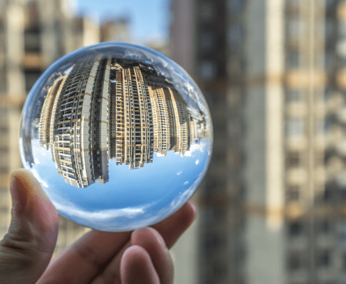 hand holding a glass ball reflecting city buildings in the background