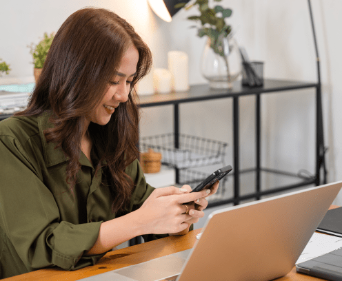 Asian business woman using laptop checking smartphone indoors home office, Happy female smile working multiple devices with computer and mobile phone, beautiful people pay digital online on desk