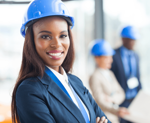 businesswoman smiling in hard hat with others out of focus in the background