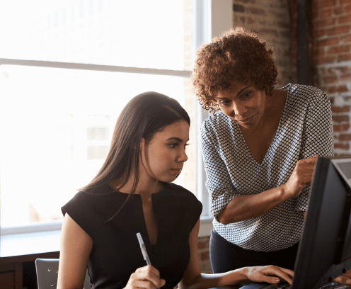 Two Businesswomen Working On Computer In Office mentor concept