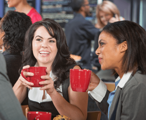 Smiling woman with coffee and friends in bistro