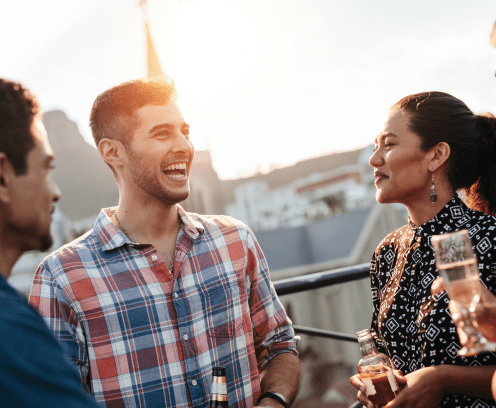 Happy young man chatting and laughing with friends. Young people having a good time together during rooftop party.