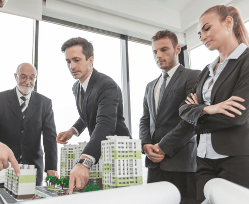 Business meeting of architects and investors looking at model of residential quarter houses