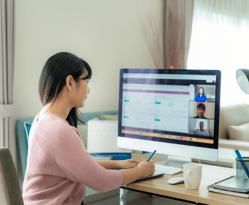 Back view of Asian business woman talking to her colleagues about plan in video conference. Multiethnic business team using computer for a online meeting in video call. Group of people smart working from home.