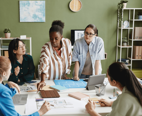 Woman architect presenting construction project to her colleagues at table during teamwork at office