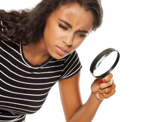 Beautiful young dark skinned woman looking trough the magnifying glass