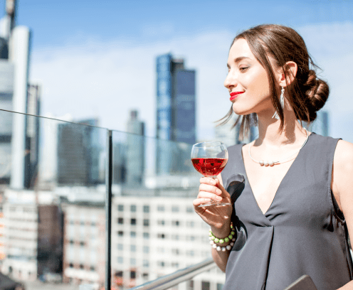 Young businesswoman enjoying wine on the terrace with great view on the skyscrapers in Frankfurt city