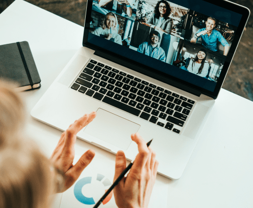 Woman has video call with her remote teammates using laptop.  White loft workspace