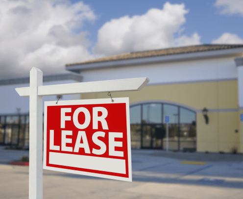 Vacant Retail Building with For Lease Real Estate Sign in Front.