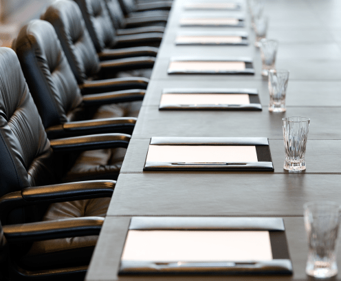 boardroom table with neatly placed papers and water glasses