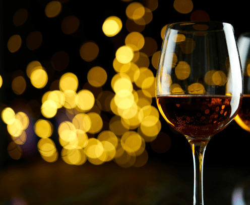 Two glasses of sparkling wine or champagne to celebrate New Year, Merry Christmas or Anniversary with a bokeh effect background. The yellow of the wine and lights stand out against a dark background.