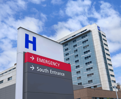 Outside of hospital with signs for Emergency and South Entrance