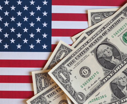 small american flag laying under eight one dollar bills