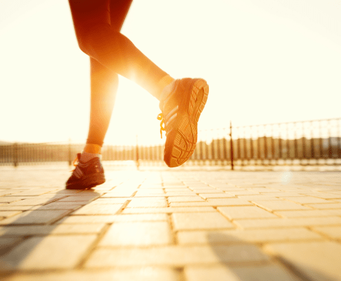 Runner feet running on road closeup on shoe. woman fitness sunrise jog workout welness concept.