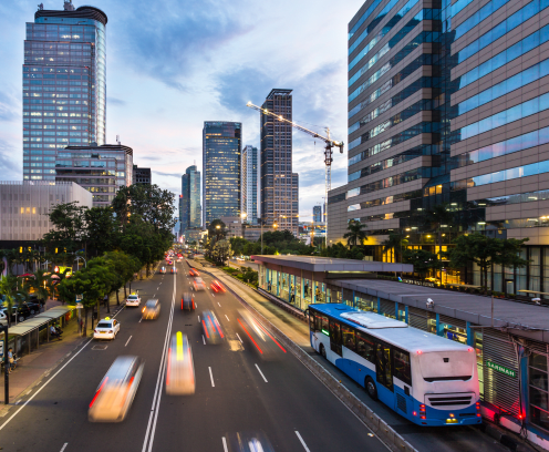Traffic rushes in Jakarta business district along the city main avenue Jalan Thamrin at sunset in Indonesia capital city. The Transjakarta bus system enjoys its own traffic lane to avoid congestion.