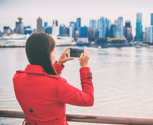 Cruise tourist woman taking pictures with mobile phone of Vancouver city leaving on Alaska cruise travel. British Columbia, Canada.