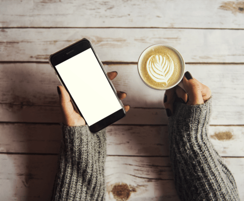 Girl holding a cup of coffee and a smart phone with copyspace