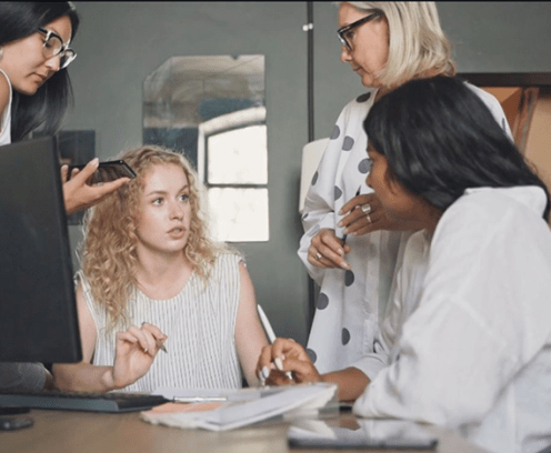 four women discussing around computer