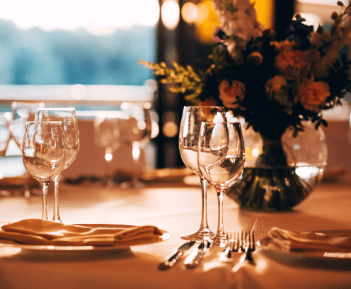 round table with a white tablecloth. the table is decorated with a vase of flowers. wine glass and champagne glass.