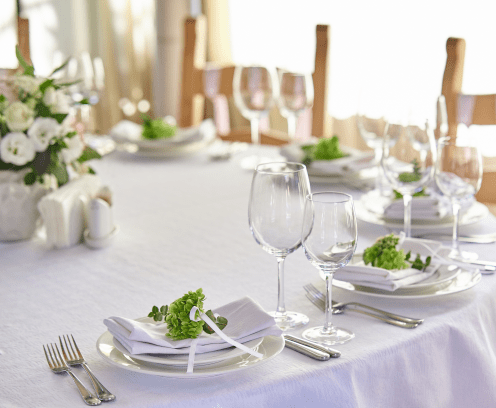 beautifully decorated festive table with plates and glasses and a bouquet of flowers in a restaurant