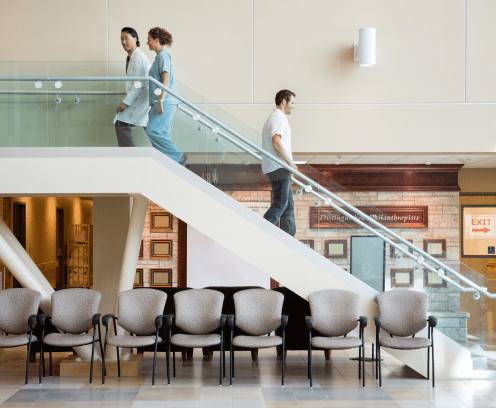 Side view of medical team and man using staircase in hospital